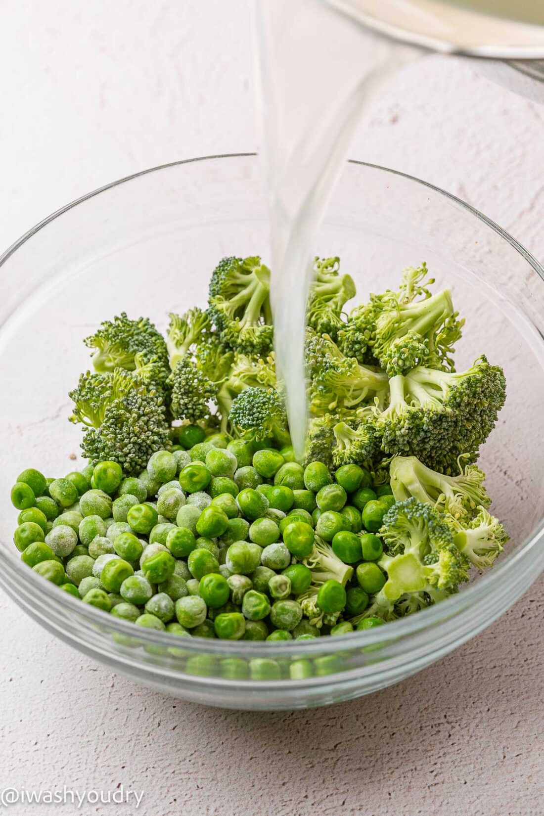 pouring hot water over broccoli and peas.