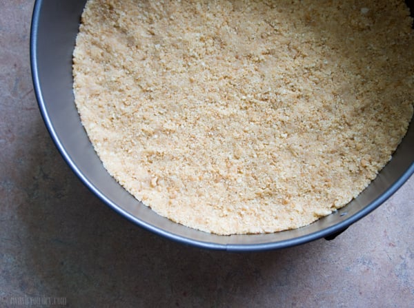 A close up of a cake pan with a base of blended cookies
