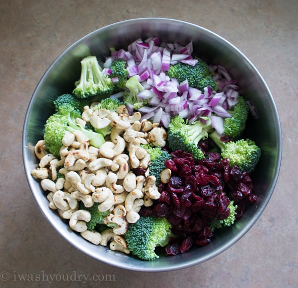 A large bowl with all the ingredients displayed to make Classic Broccoli Salad