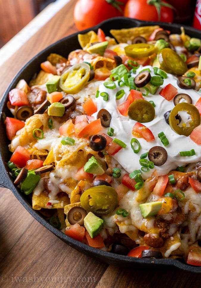 nachos in pan with sour cream, olives and pickled jalapenos