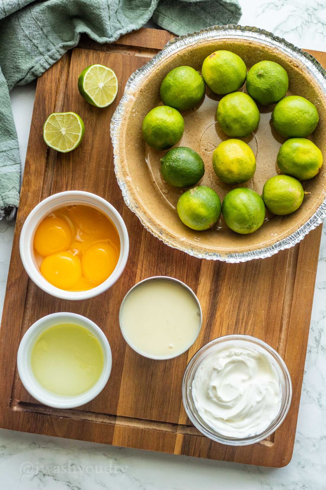Ingredients for key lime pie in glass bowls on wood cutting board 