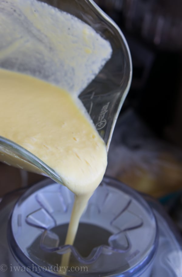 A close up of a glass blender jar pouring it\'s liquid contents