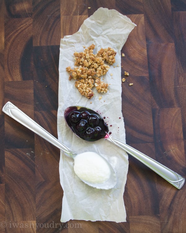 oat crumble, blueberry compote and vanilla ice cream on wood surface with spoons. 