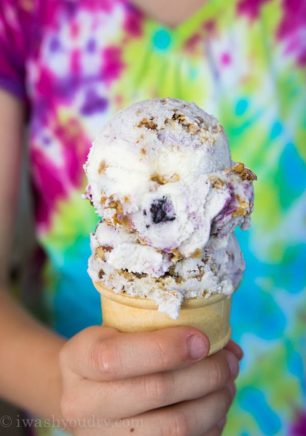 two scoops of ice cream in cone with hand holding it.