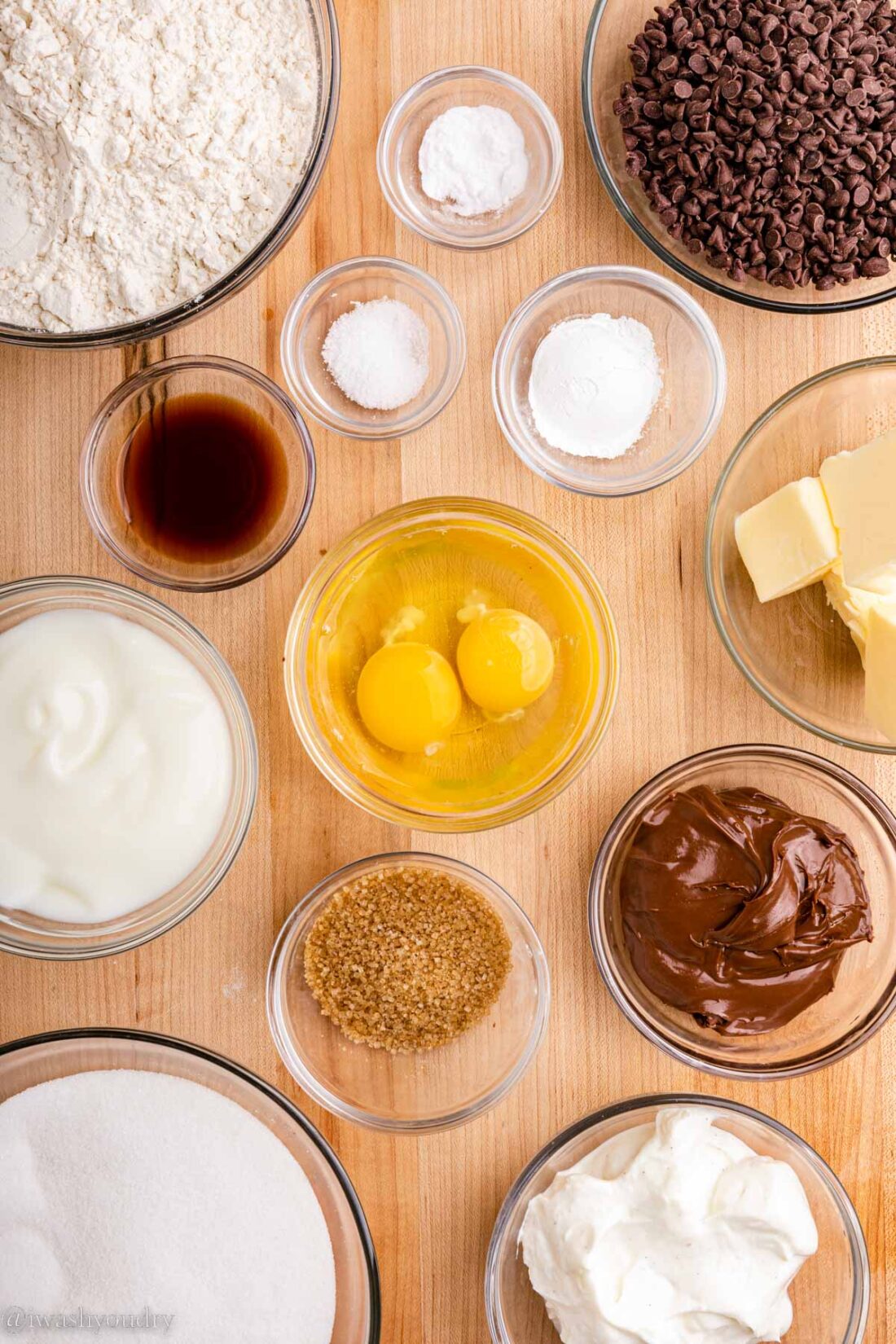 Ingredients for chocoalte chip nutella muffins in glass bowls on wood countertop.. 