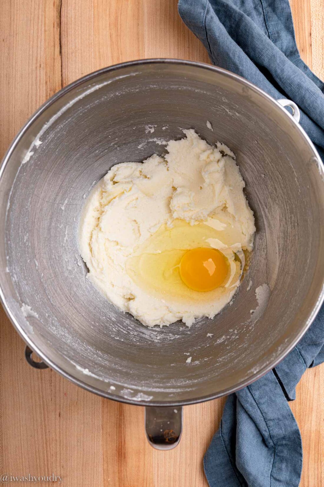 Butter and sugar mixture with an egg in metal mixing bowl. 