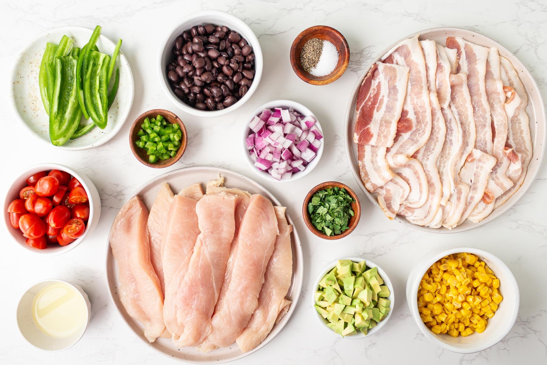 Ingredients for bacon wrapped chicken and cowboy caviar on table with jalapenos.