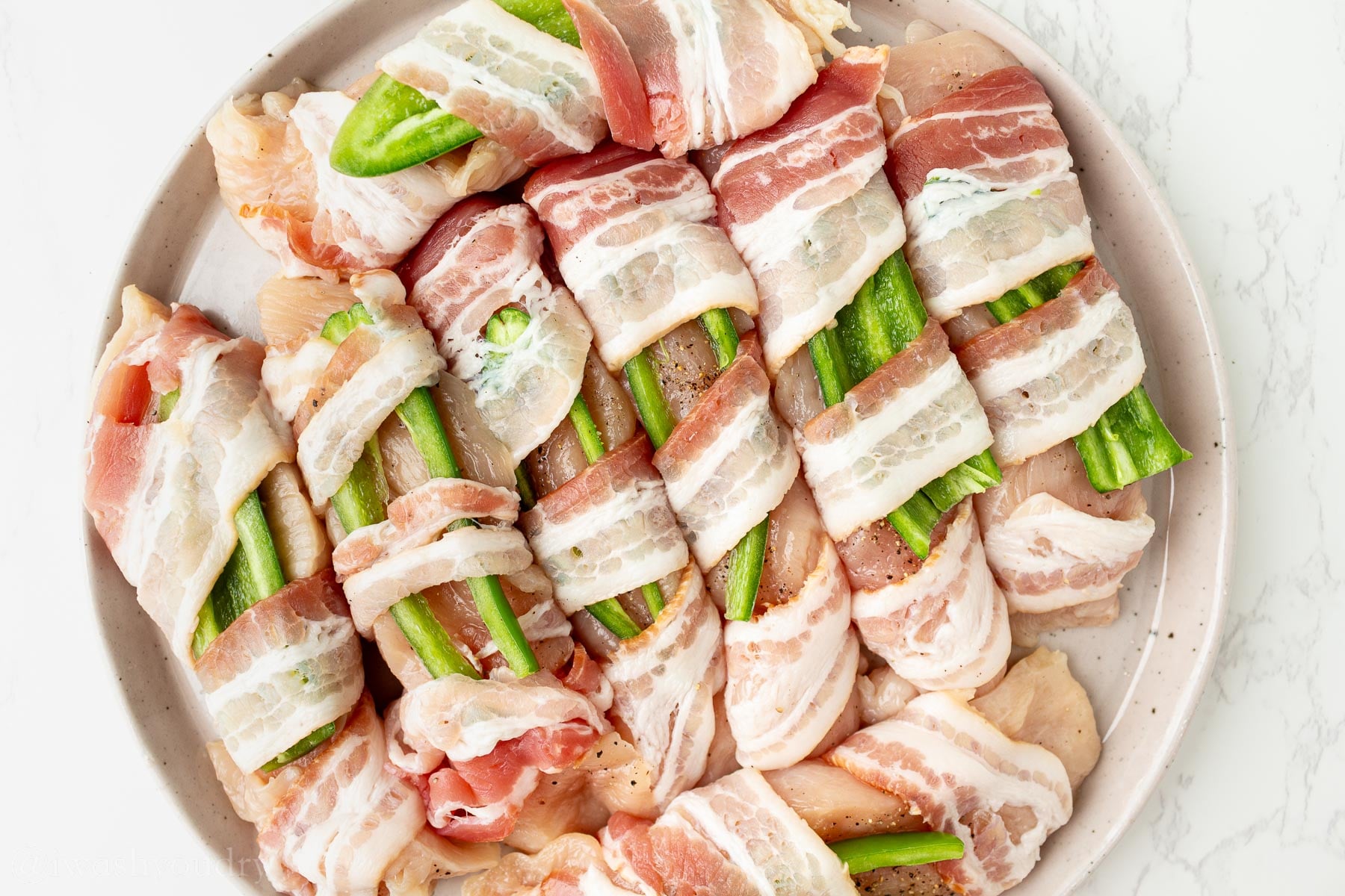 Chicken wrapped in bacon with a slice of jalapeno tucked into it.