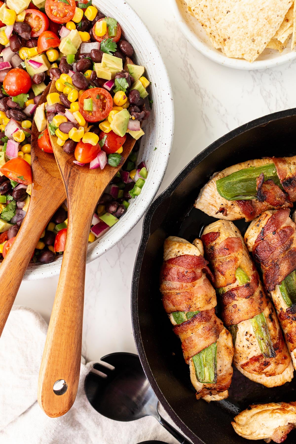 bowl filled with cowboy caviar and skillet filled with spicy bacon wrapped chicken.