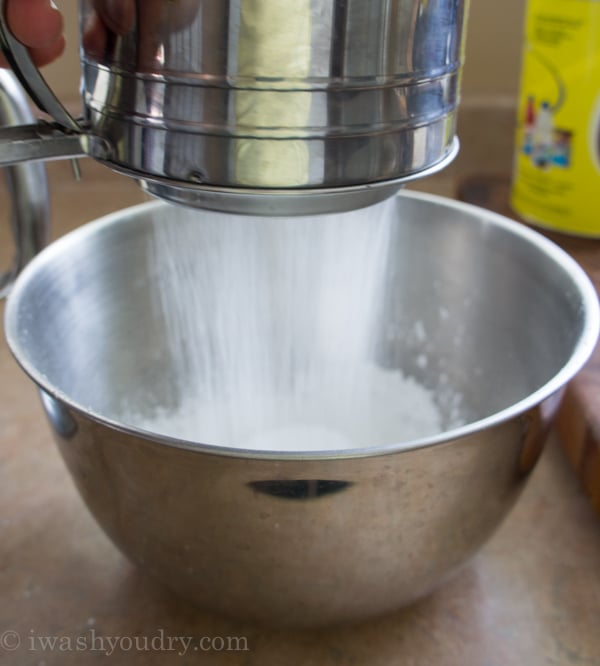 Powdered sugar being sifted into a metal bowl