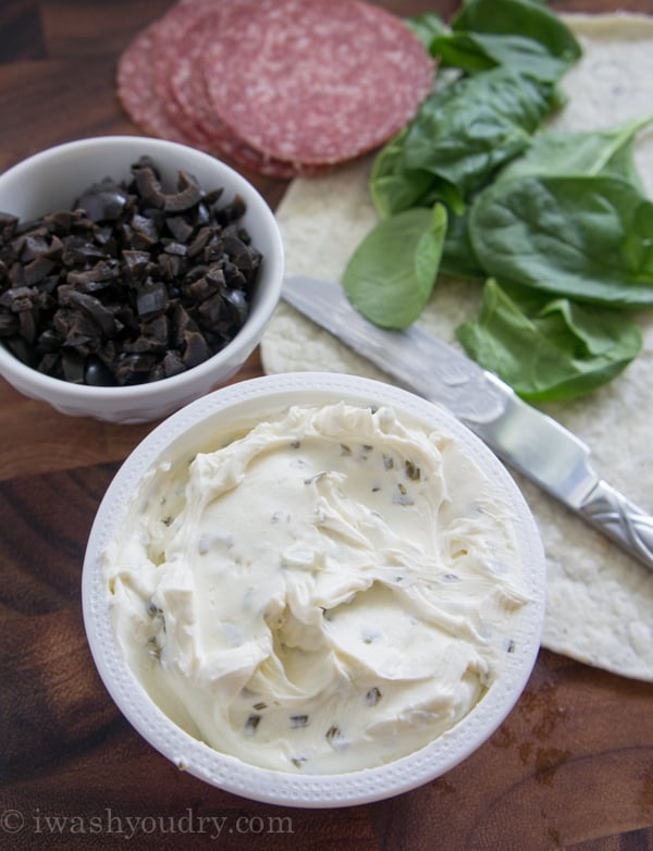 food on a table, with a. owl of cream cheese, a bowl of chopped olives and a small pile of spinach