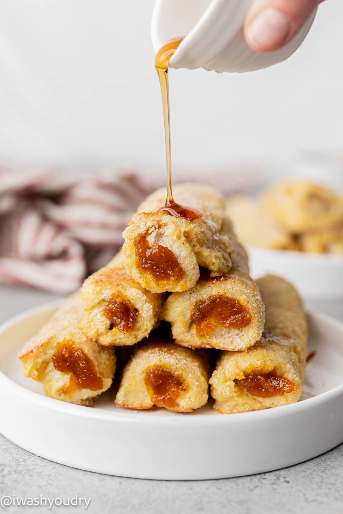 pyramid of french toast stuffed with pumpkin, maple syrup pouring on top.