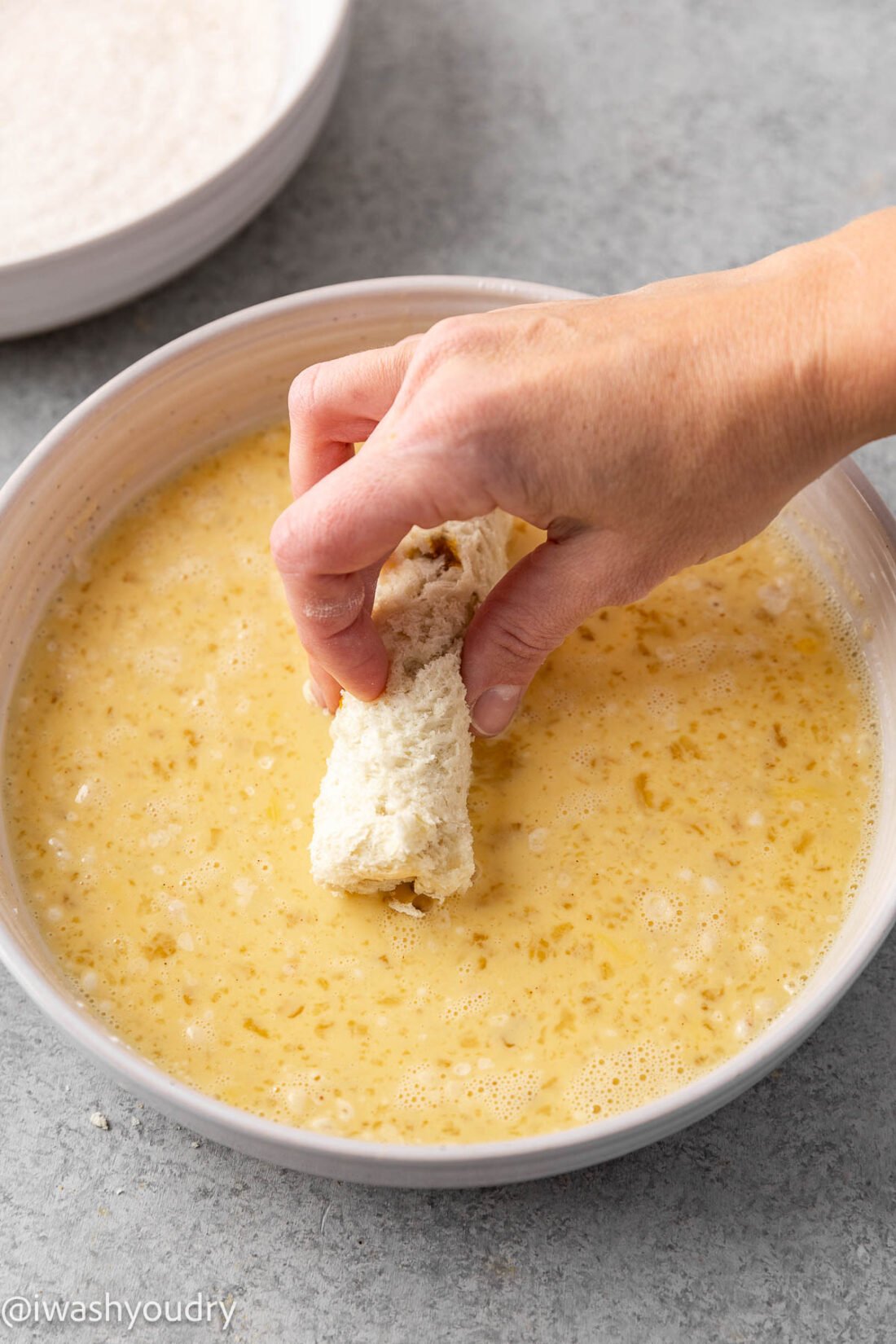 dipping french toast stick in batter.