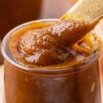 Cooked pumpkin butter in jar with spoon.