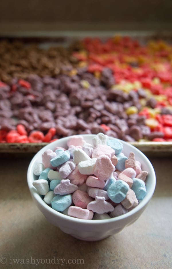 a close up of small colorful marshmallows in front of a colorful pan of rice crispy treats