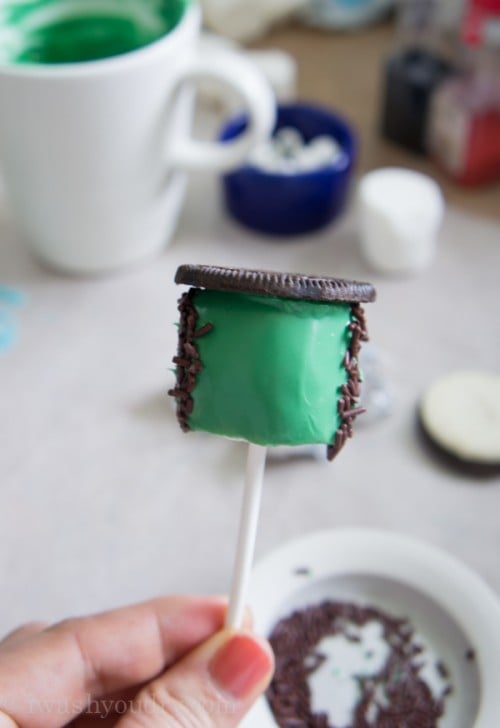 A close up of the making of a Halloween themed marshmallow pop