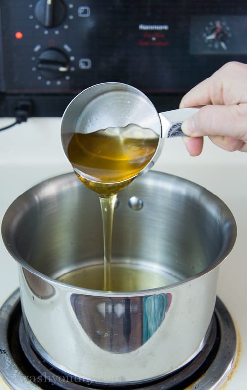 Honey being poured from a measuring cup into a pan