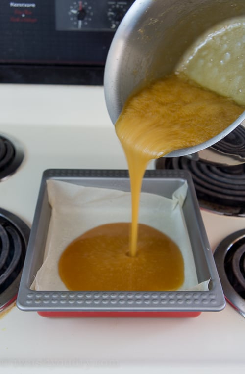 Melted liquid being poured from a pan to a parchment lined baking dish