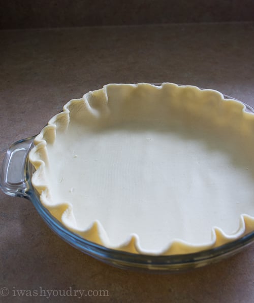 A glass pie dish with a raw crust laid inside 