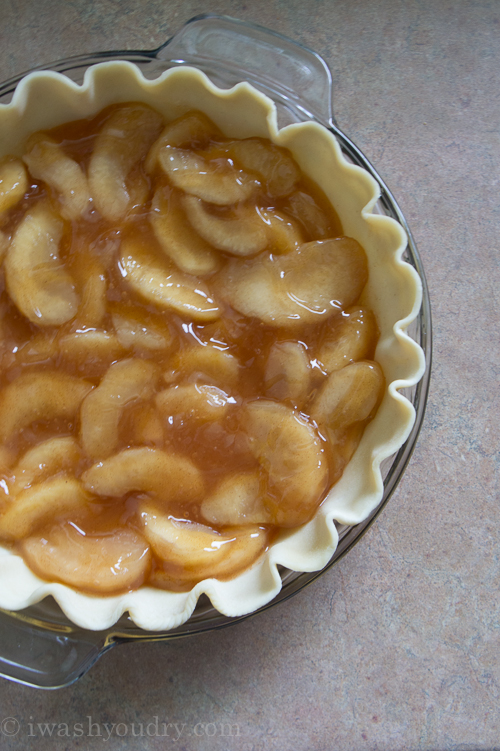 A close up of apple pie base inside a pie dish with raw crust