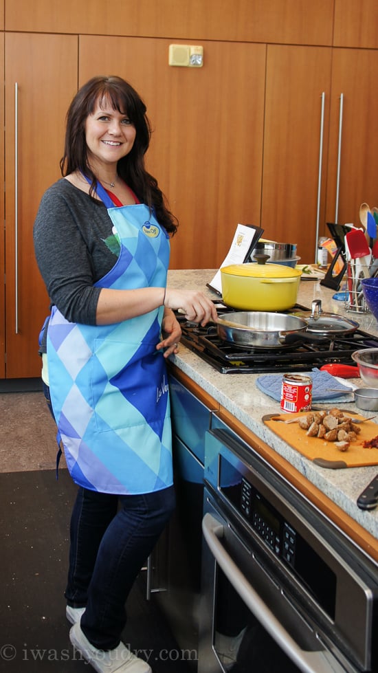 A woman standing at a stove in a kitchen with a pan on the stovetop