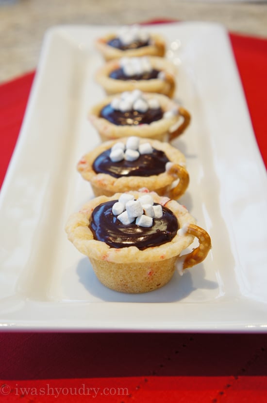 A plate of mini muffin shaped crusts made to look like a mug with chocolate filling topped with mini marshmallows