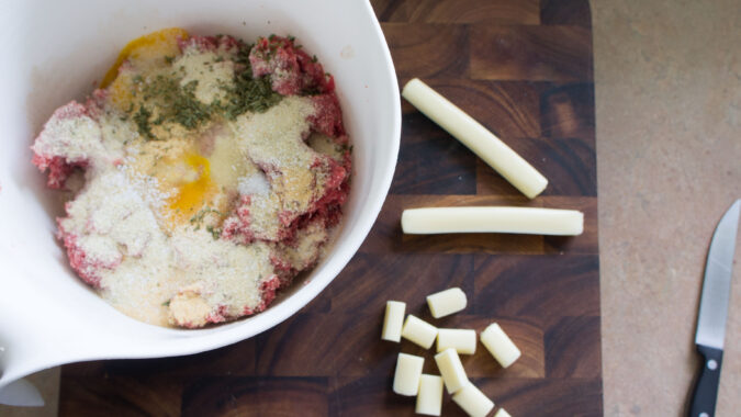 Meatball mixture in bowl with cheese strings beside it