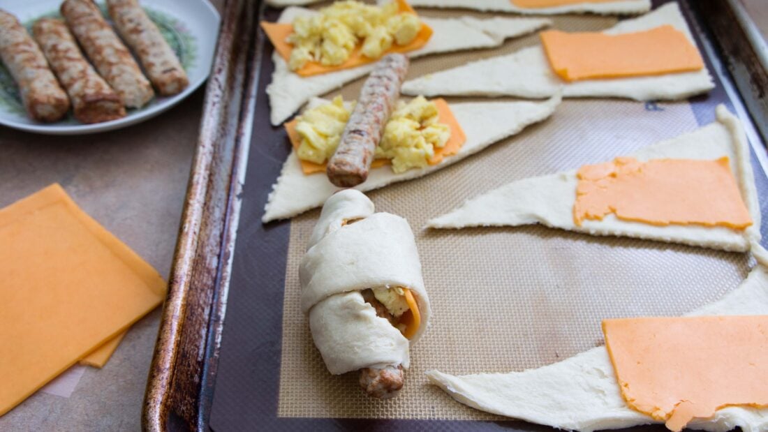 assembling sausage roll ups on baking sheet.