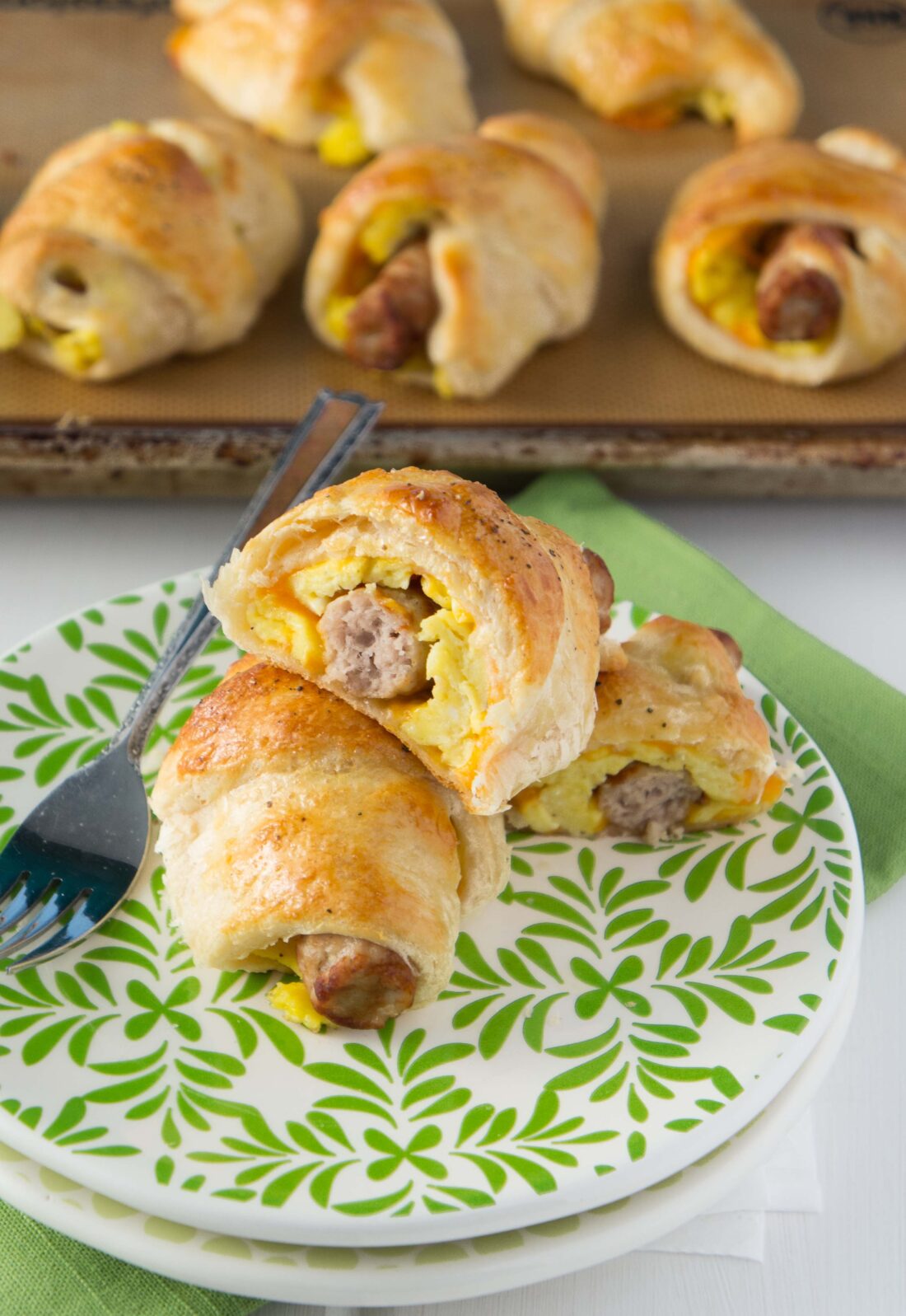 sausage egg and cheese breakfast roll ups on green plate.