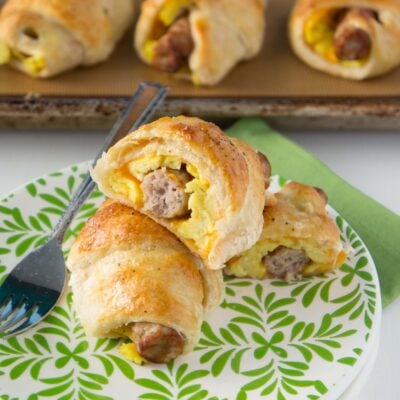 sausage egg and cheese breakfast roll ups on green plate.