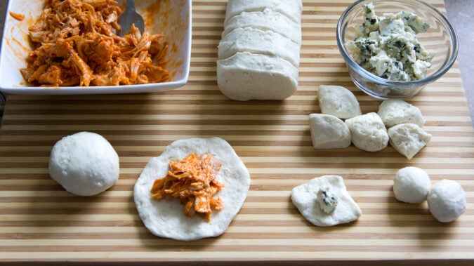 Ingredients displayed for the recipe showing raw dough flattened and shredded chicken in the center