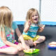 Two little girls eating sandwiches on a trampoline