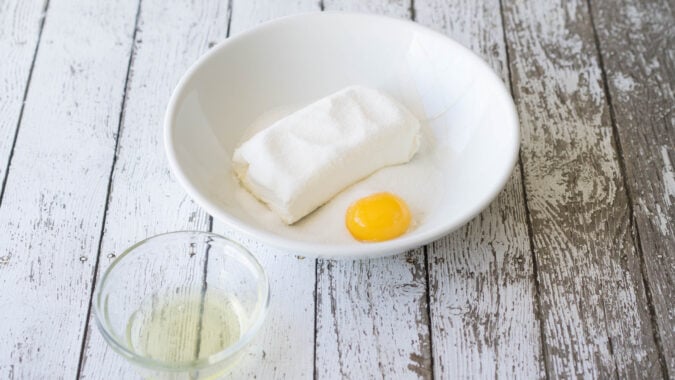 cream cheese, egg and egg white in white bowl on surface.