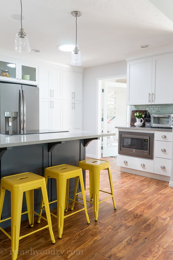 Love the yellow barstools and mini pendant lights above the island! Gorgeous white kitchen with grey slate appliances by GE. 