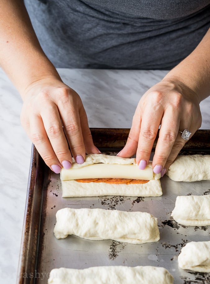 rolling pizza dough on baking sheet.