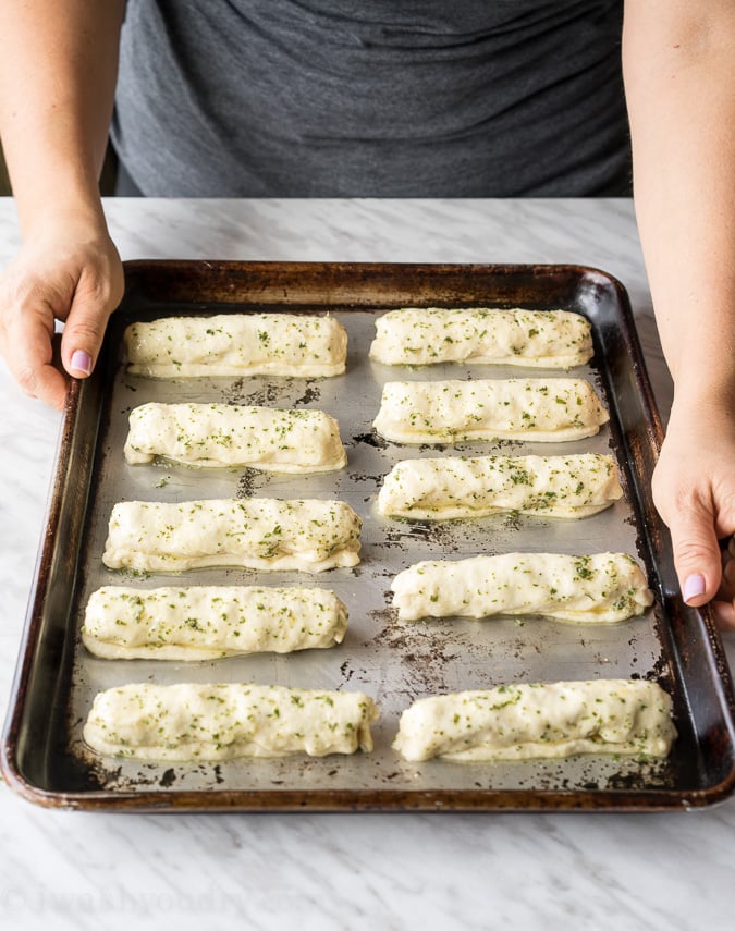 tray of pizza sticks with hands on tray.