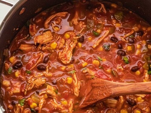 black pot filled with red chicken tortilla soup with black beans.