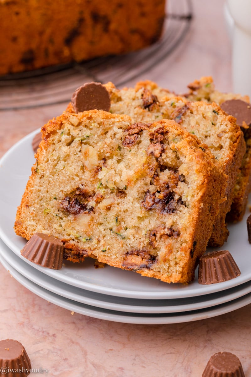 Baked chocolate peanut butter cup zucchini bread sliced on white plates with mini peanut butter cups. 