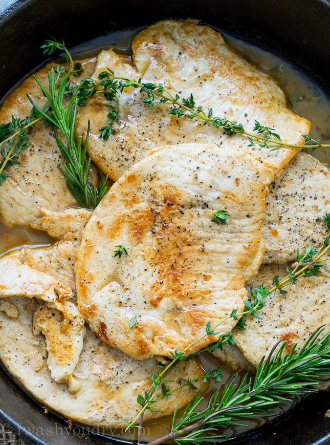 Cooked turkey cutlets with herbs in cast iron skillet. 