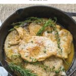 Cooked turkey cutlets in black skillet with herbs.