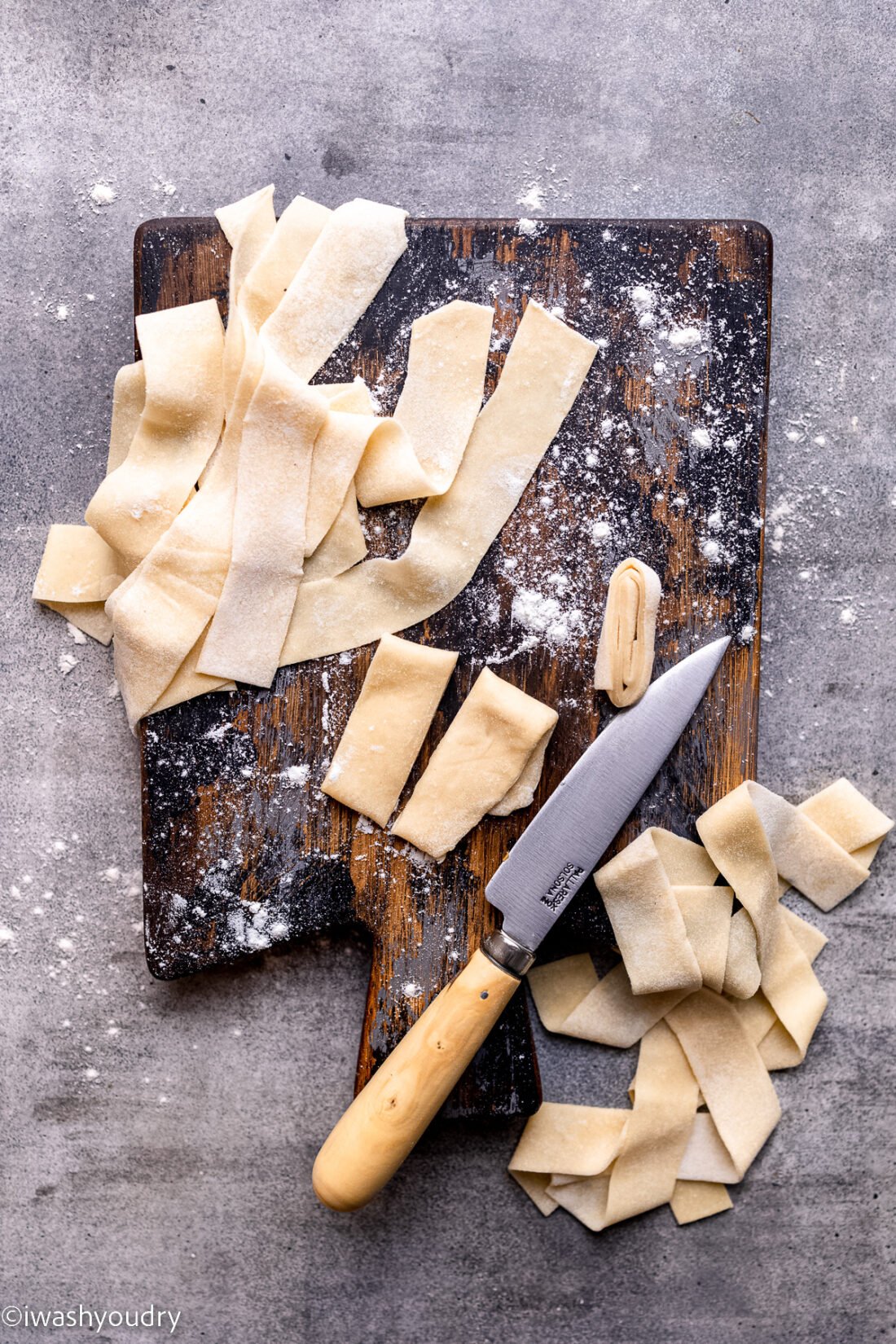 Raw noodle dough on wood cutting board with knife. 