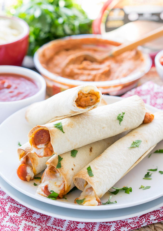These Pizza Hummus Taquitos are a cheesy, crispy baked snack or appetizer that my kids go nuts for! They're so easy to make too! 