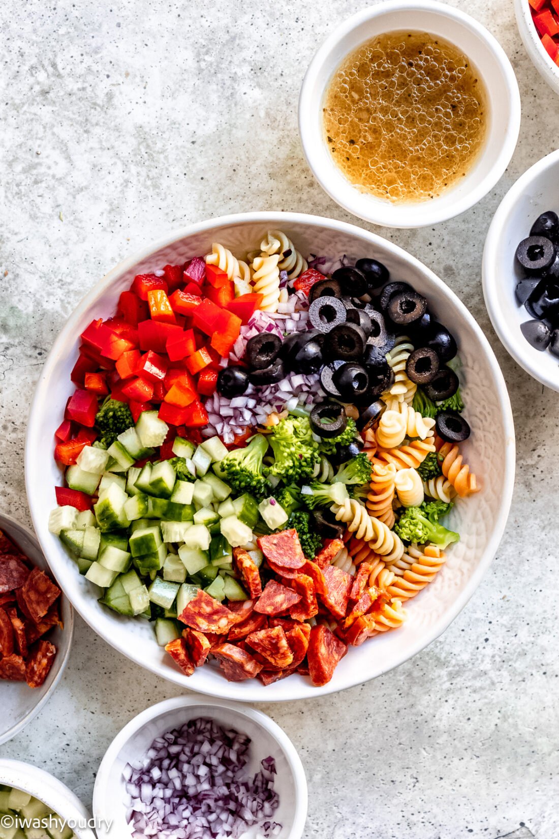 chopped veggies and pepperoni in white bowl with pasta and broccoli.