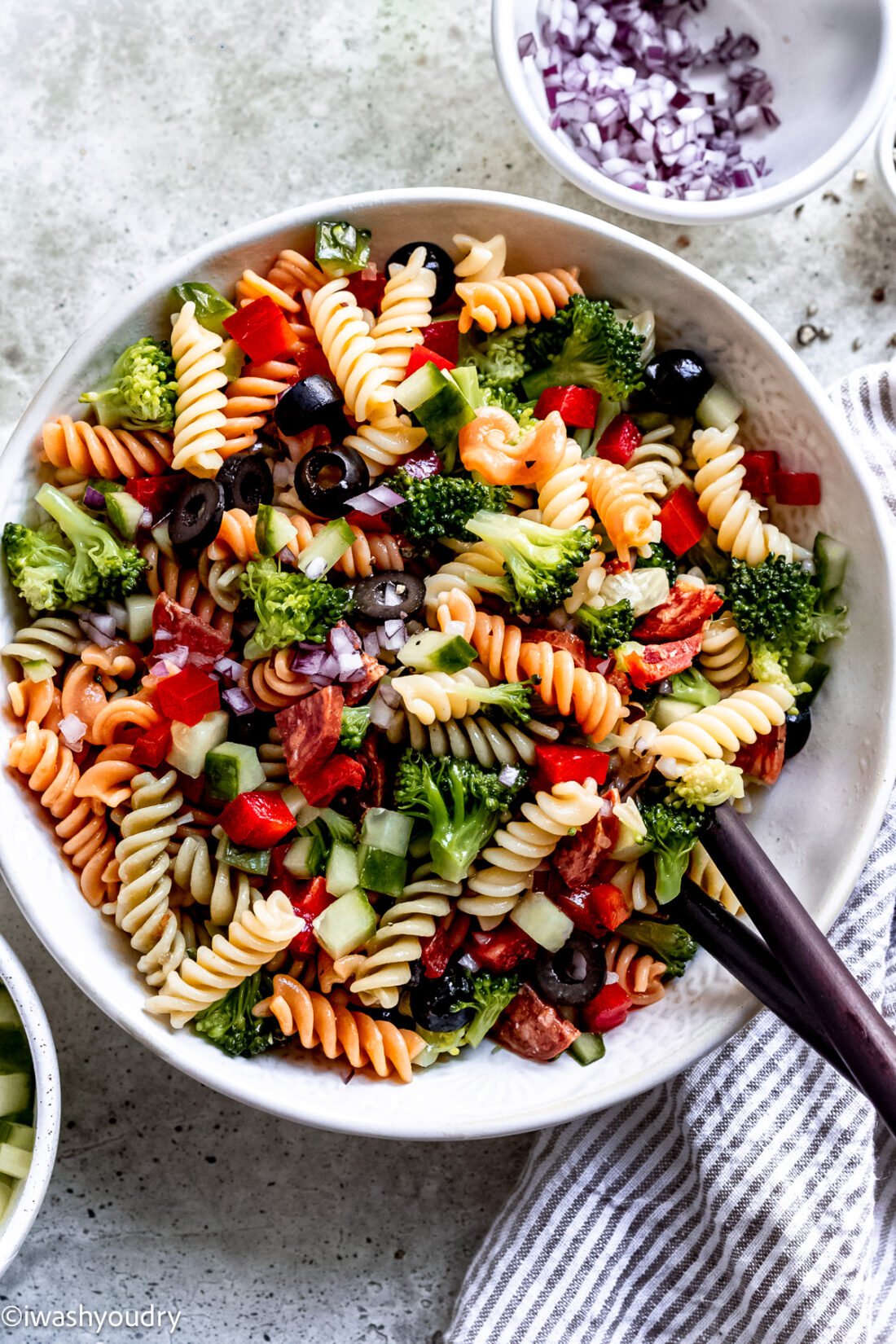 pasta salad recipe in bowl with wooden spoon.