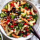 pasta salad recipe in bowl with wooden spoon.