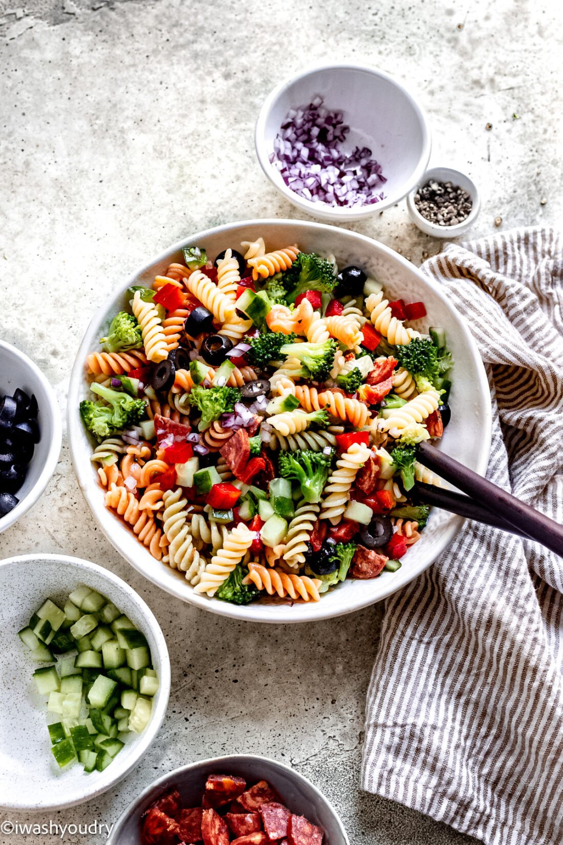 bowl of italian pasta salad with wooden spoon for party.