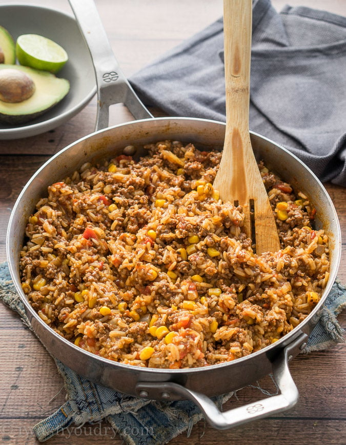 Skillet with cooked beef and rice with avocado, tomato, and sour cream