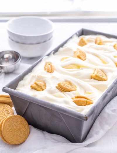 A rectangle pan on a table, with ice cream and vanilla sandwich cookies in it
