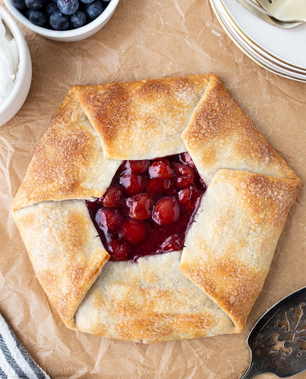 Cherry galette on parchment paper with golden brown and flakey pie crust.