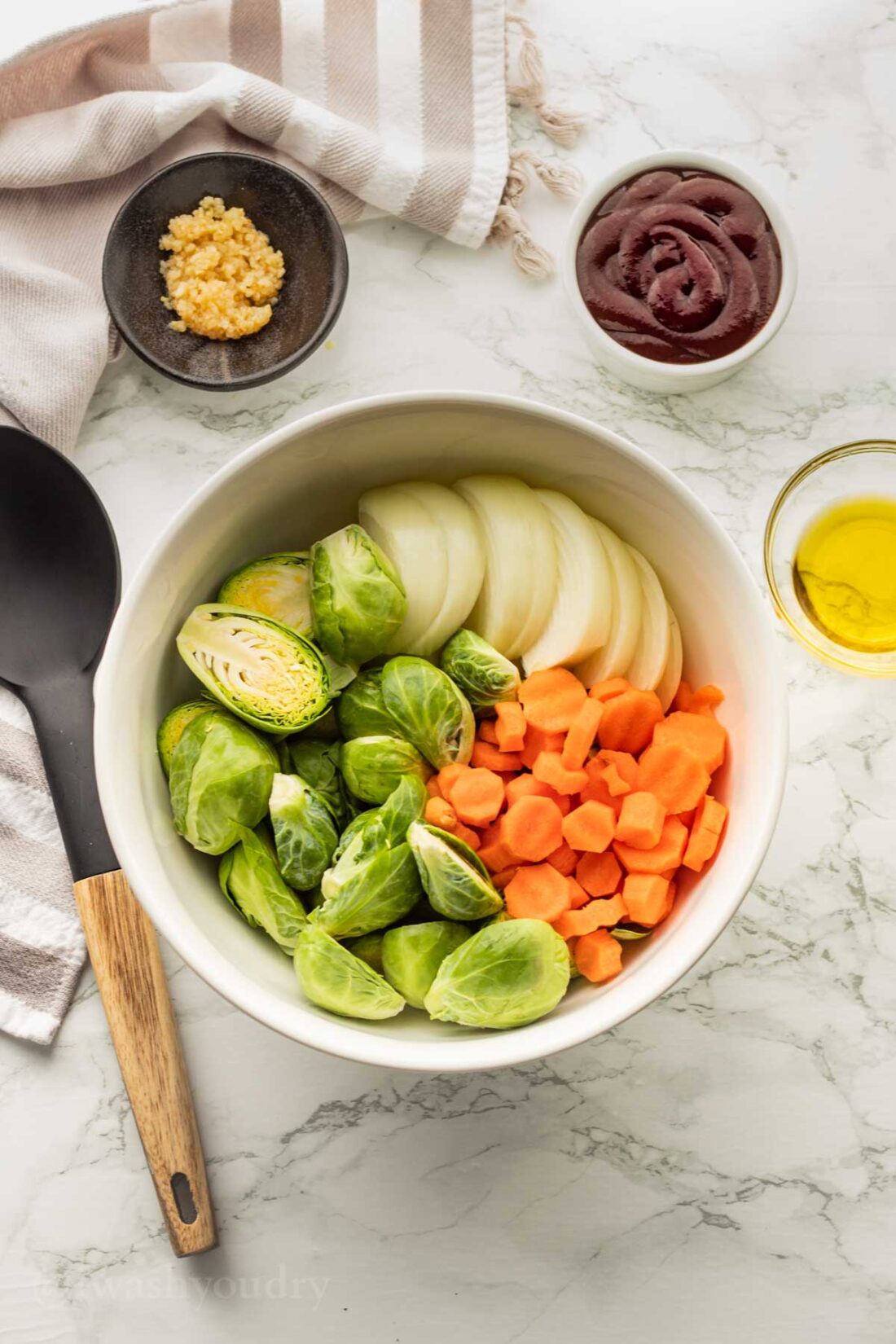 Brussels Sprouts, carrots, and onions in white bowl. 